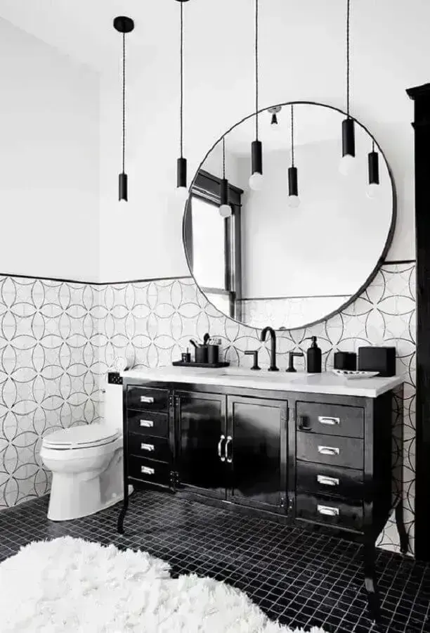 Decoração de banheiro com piso preto e espelho redondo