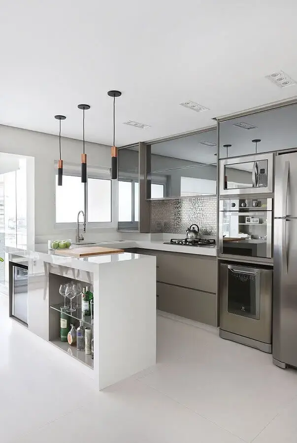 Decoração de cozinha planejada com armários espelhados e luminária pendente moderna para bancada