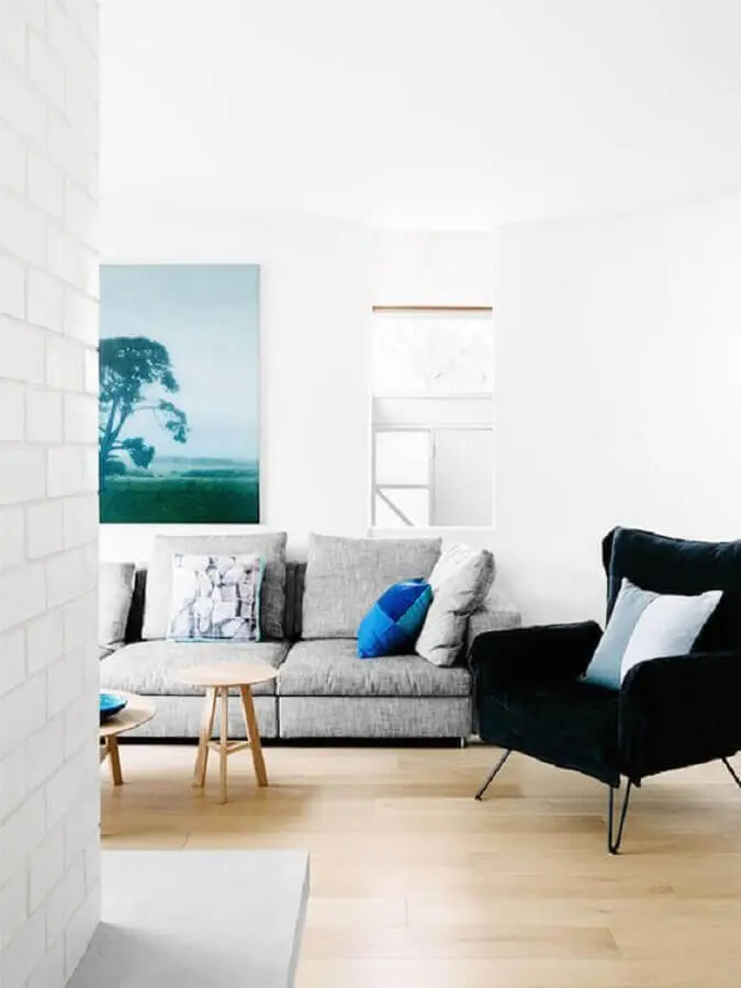Decoração de sala branca com sofá cinza e poltroan preta confortável