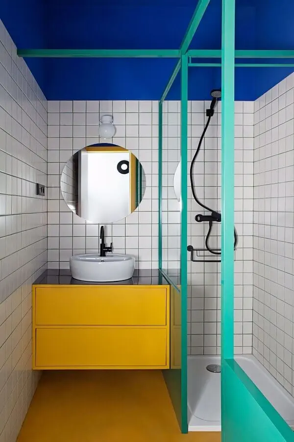 Decoração moderna para banheiro pequeno com gabinete amarelo e box cor verde água