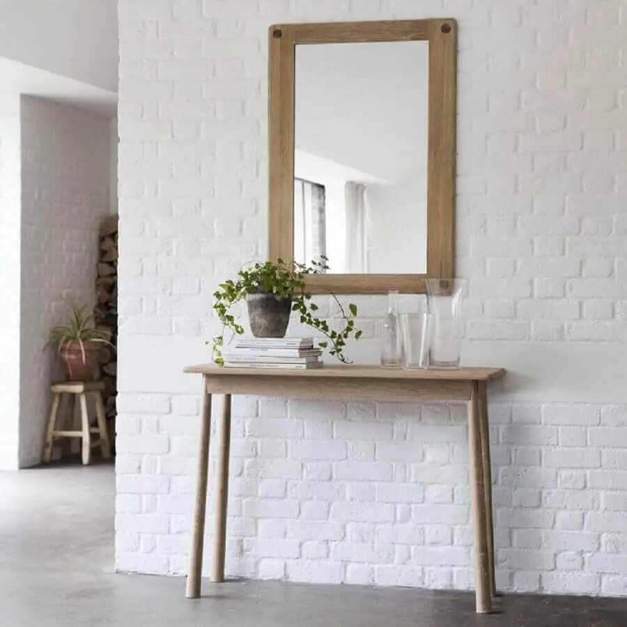 Decoração simples com aparador com espelho para corredor com parede de tijolinho branco
