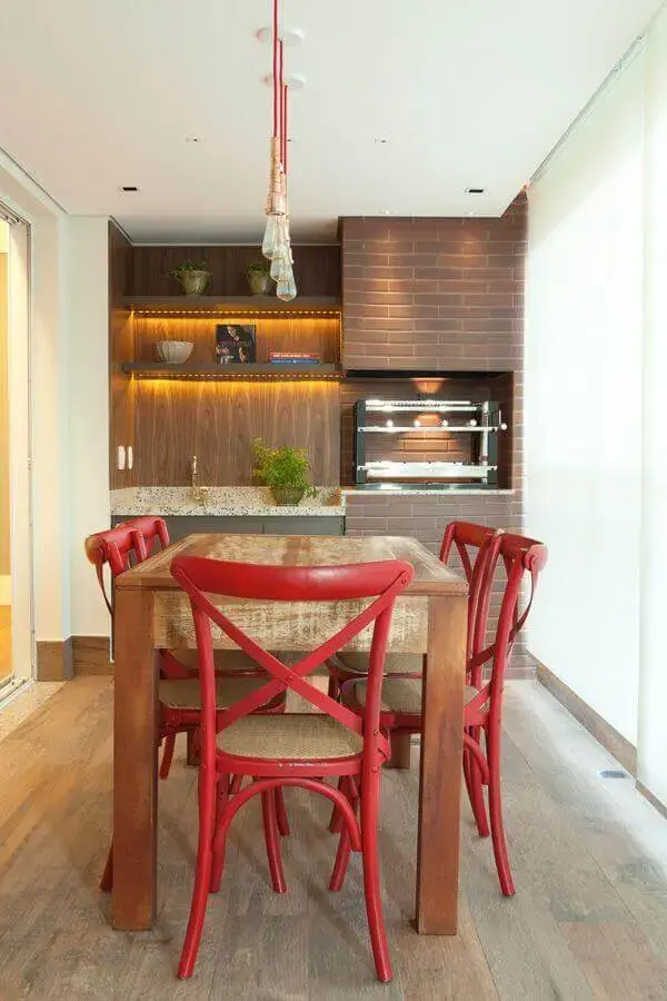 Pendente para área gourmet com churrasqueira decorada com cadeiras vermelhas para mesa de madeira