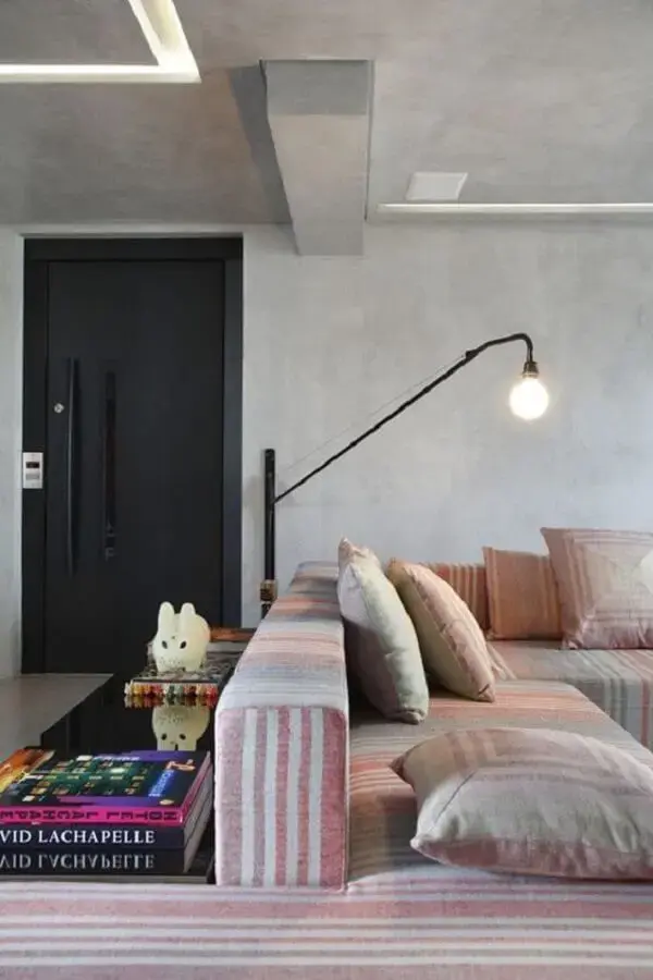 Sala de estar decorada com cimento queimado e luminária de parede moderna