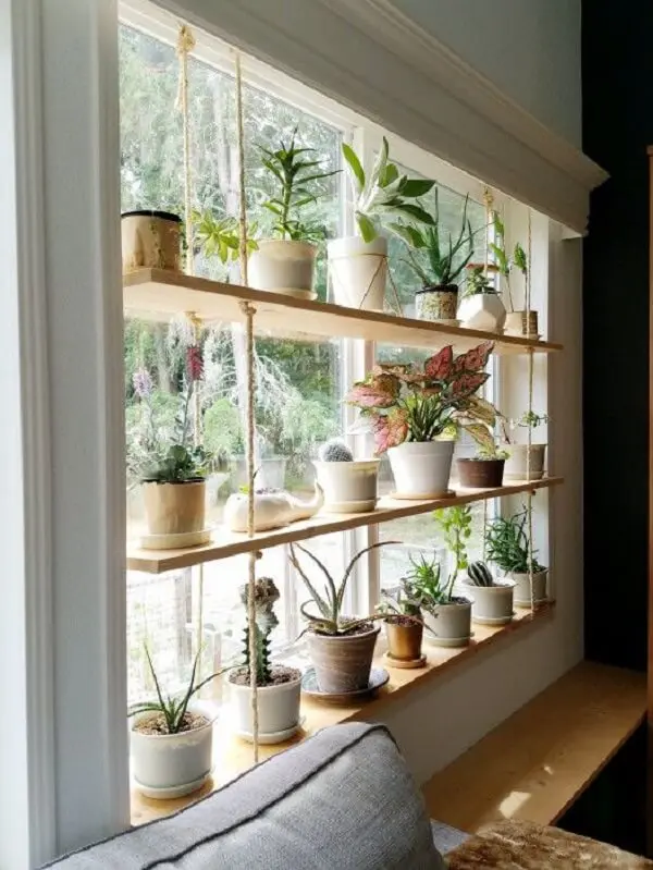 A prateleira suspensa serve de apoio para os vasos de plantas e ajuda na decoração da janela. Fonte: The Artful Roost