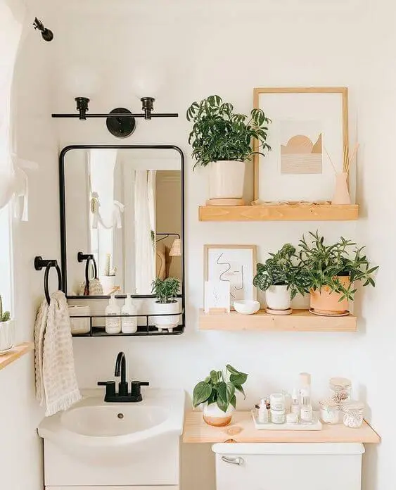 Banheiro com prateleira rustica e decoração com quadros e plantas