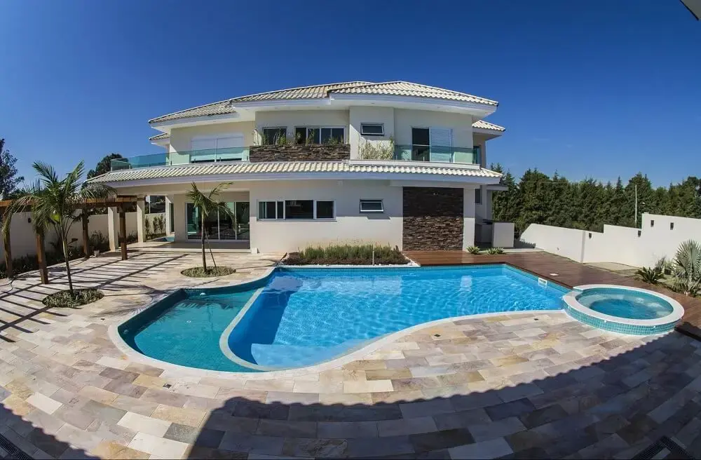 Casa com piscina redonda interligada a piscina com formato orgânico. Fonte: Sodramar