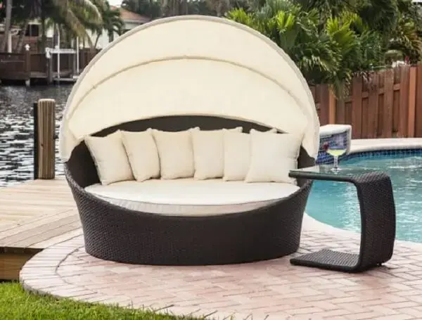 Esse modelo de sofá de vime redondo fica perfeito na área da piscina