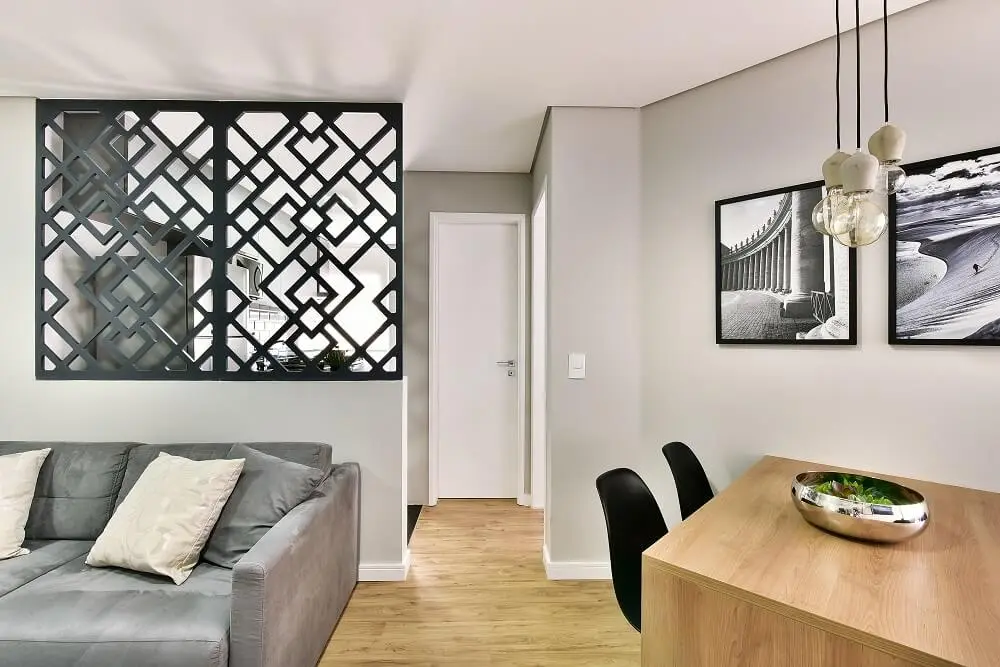 O painel vazado com figuras geométricas busca delimitar os ambiente da sala de estar e cozinha. Foto: Sidney Doll