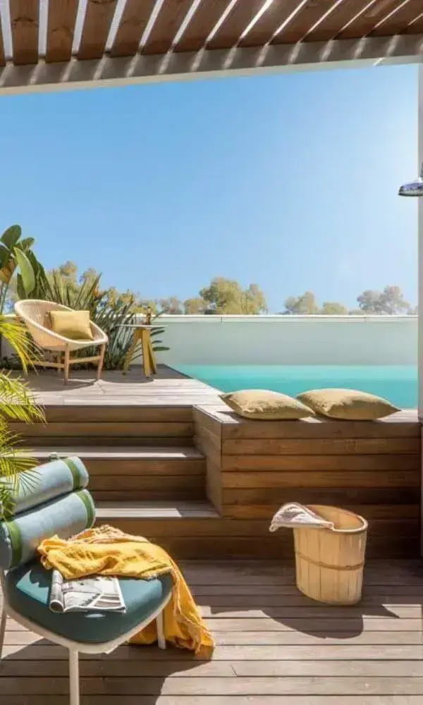 Piscina elevada com deck de madeira e móveis confortáveis para tomar sol