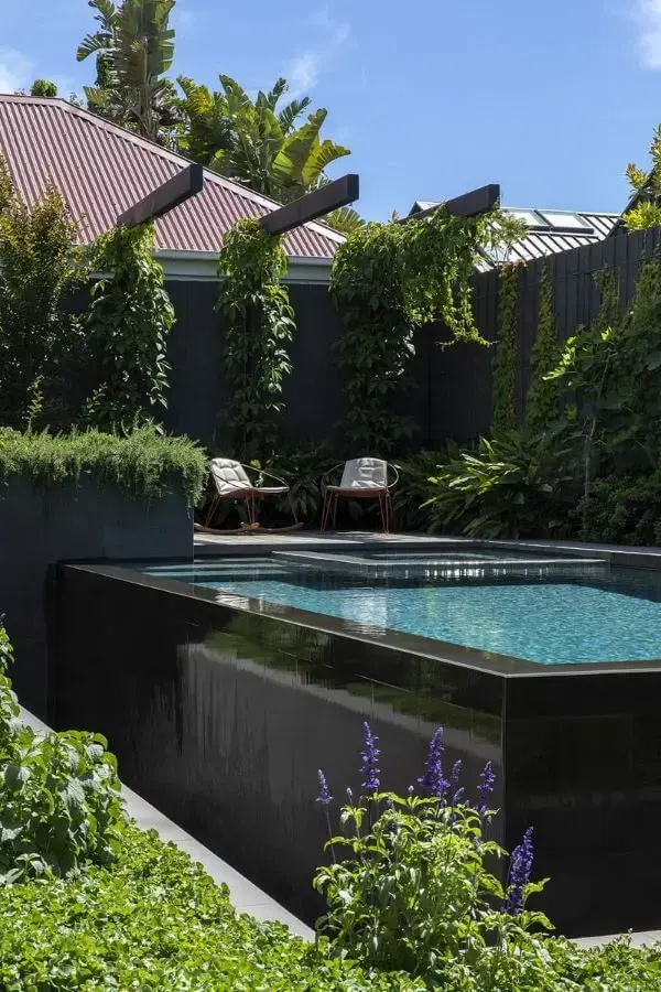Piscina elevada preta com decoração de jardim