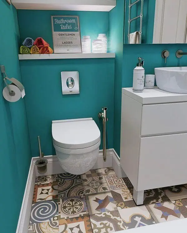 Piso colorido em ladrilho hidráulico e marcenaria branca decoram o banheiro
