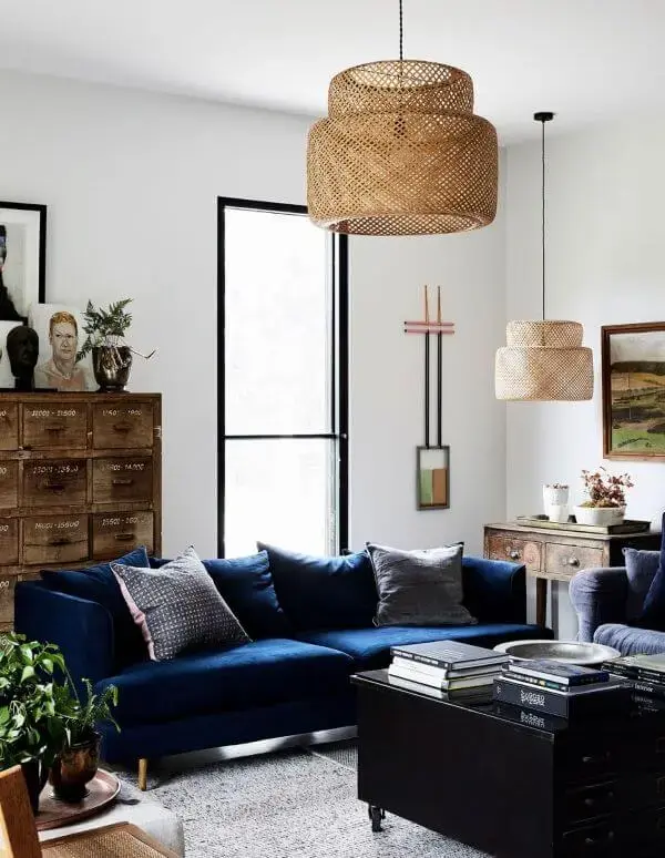 Sala clara com sofá azul marinho e lustre rustico