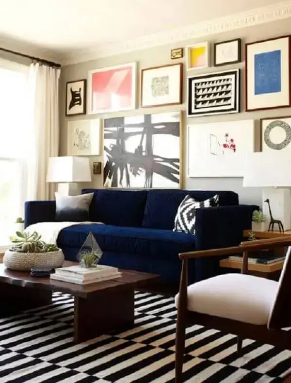 Sala com sofá azul marinho e conjunto de quadros na parede