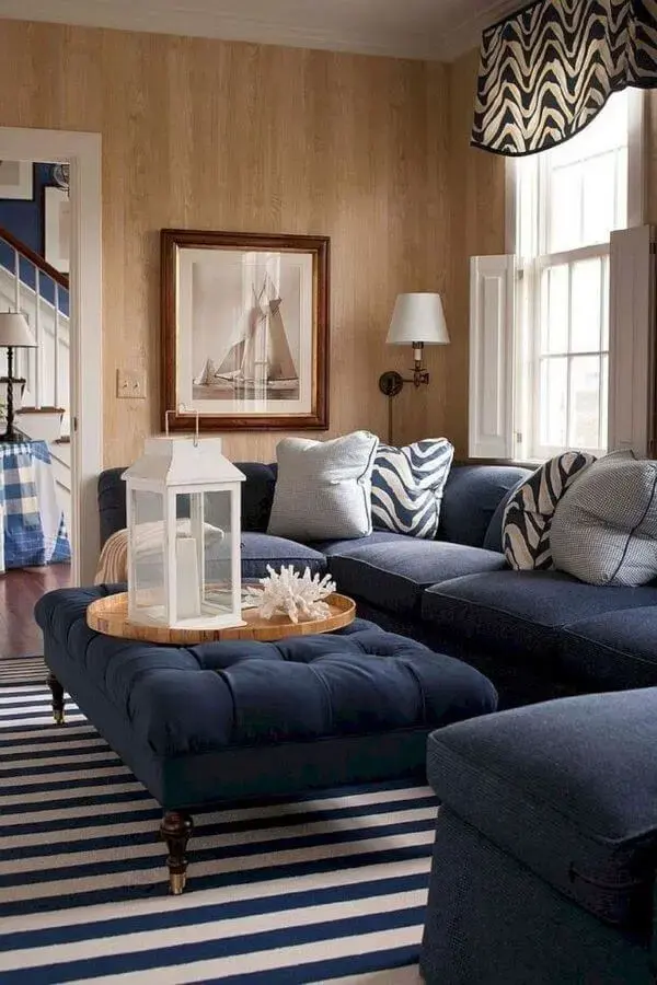 Sala com sofá azul marinho e puff na mesma cor 