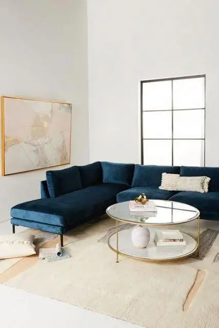 Sala minimalista e branca com sofá azul marinho de canto