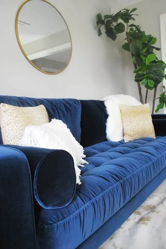 Sofá azul marinho de veludo com almofadas brancas