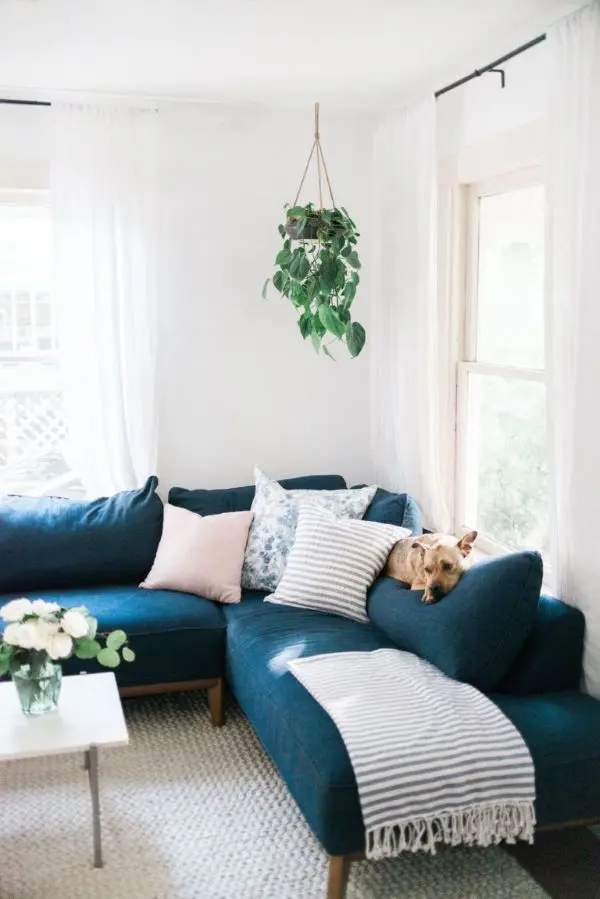 Sofá de canto azul marinho com manta e almofadas neutras