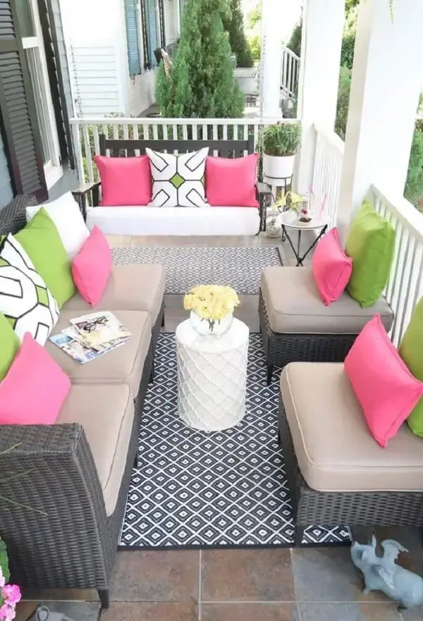 Tons de rosa e verde invadem a decoração dessa varanda com sofá de vime
