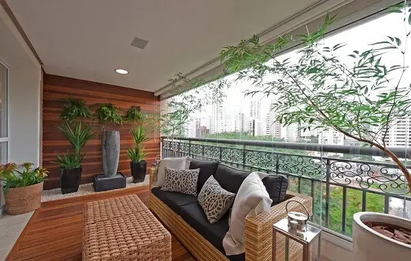 Varanda ampla decorada com um lindo sofá de vime e vasos de plantas