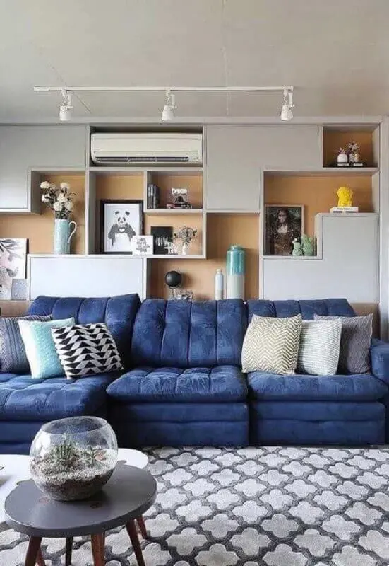 almofadas diferentes para sala de TV moderna decorada com sofá azul e parede de nichos Foto Pinterest
