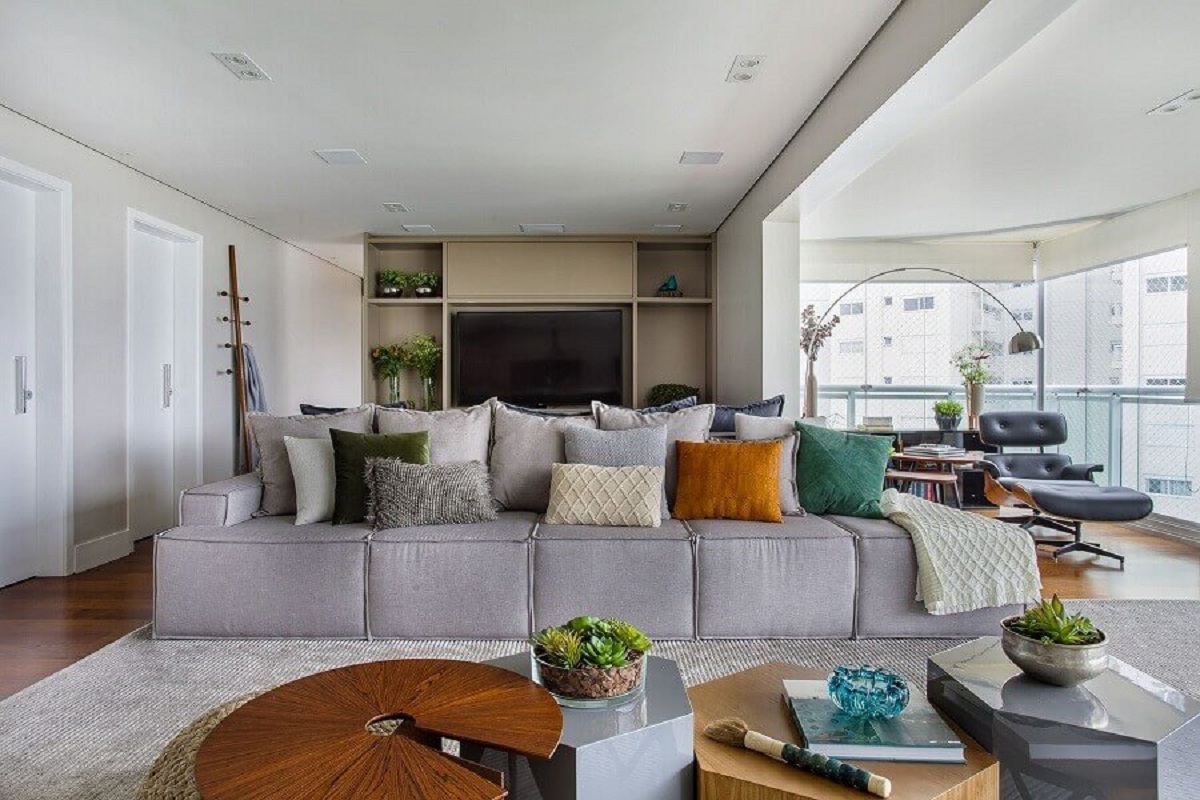almofadas diferentes para sala grande moderna integrada com varanda de apartamento Foto Tria Arquitetura