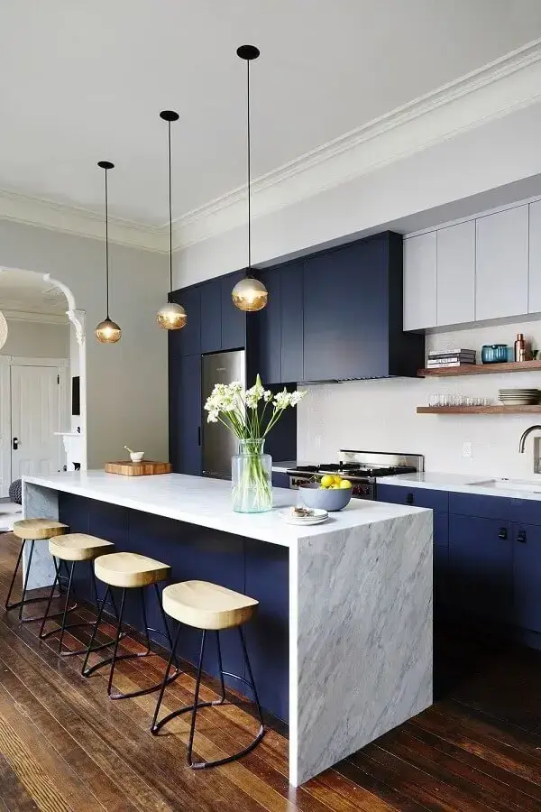 cozinha com balcão de mármore no meio decorada com armários azuis Foto McGee & Co.
