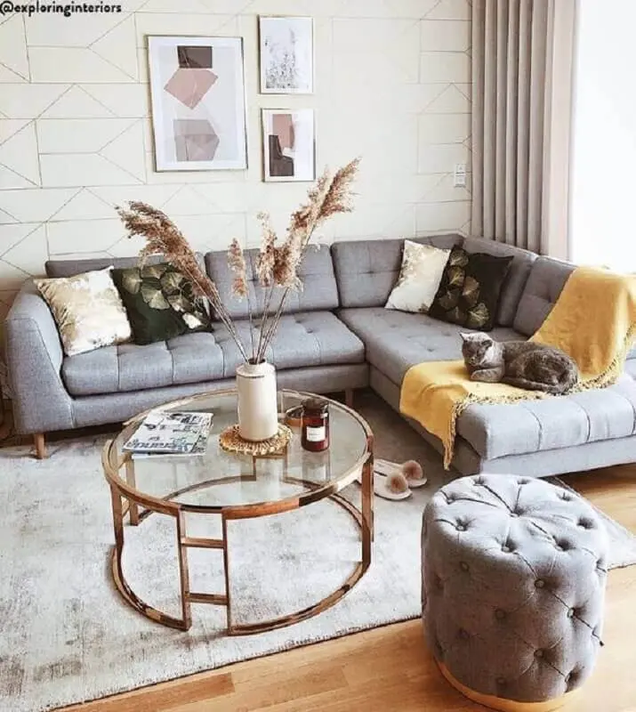 mesa de centro redonda de vidro para sala decorada com sofá de canto cinza e puff capitonê Foto Jeito de Casa