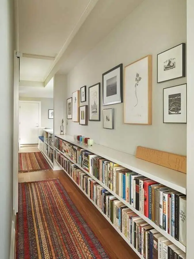 parede com quadros para corredor decorado com estante de livros Foto Histórias de Casa