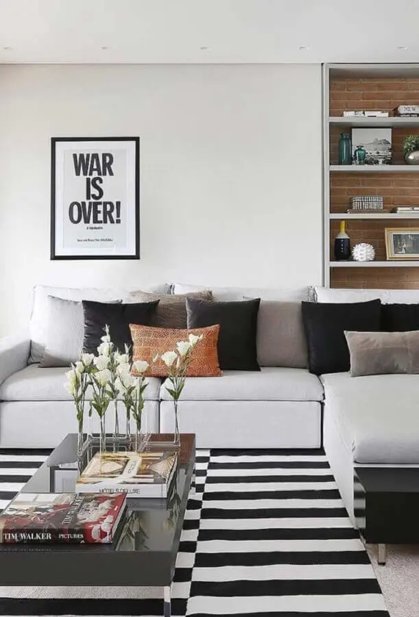 sofá com chaise com almofadas para sala decorada com tapete listrado Foto Histórias de Casa