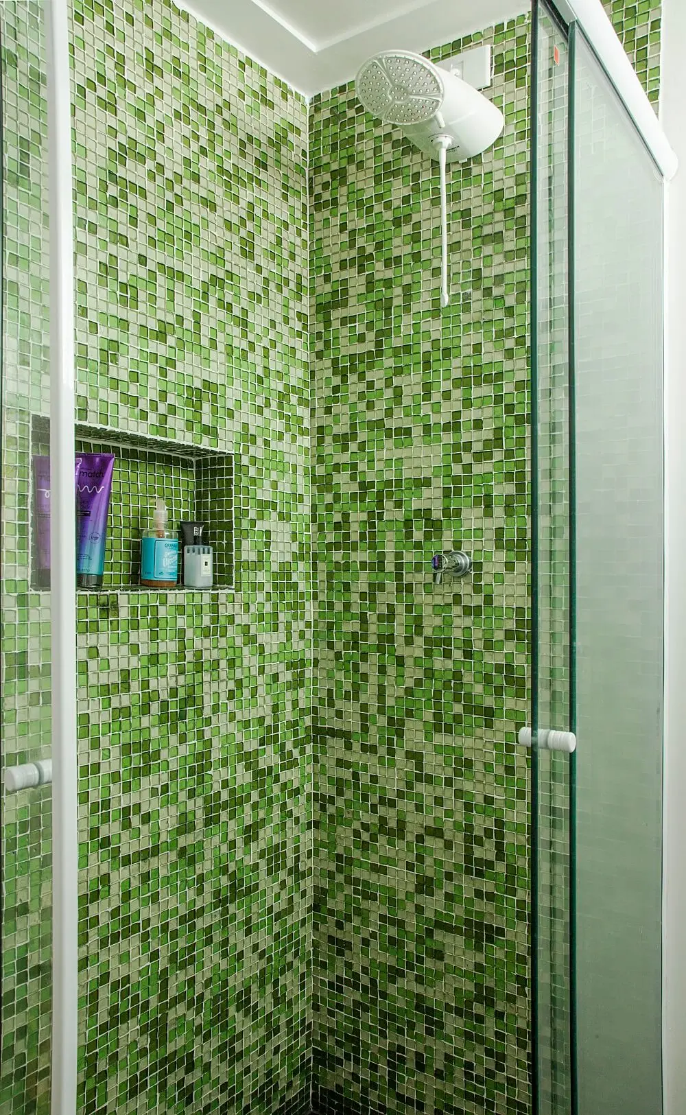 Na área do banho as pastilhas de vidro verde trazem um toque de cor para o cômodo. Foto: Luis Gomes