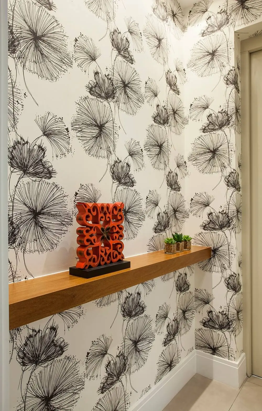 A decoração tanto da entrada do elevador como do lavabo seguem o mesmo papel de parede floral. Foto: Eduardo Pozella