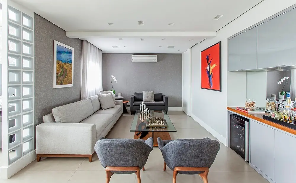 Para a sala de estar sofá branco, poltronas em tom cinza e quadros coloridos. Foto: Eduardo Pozella