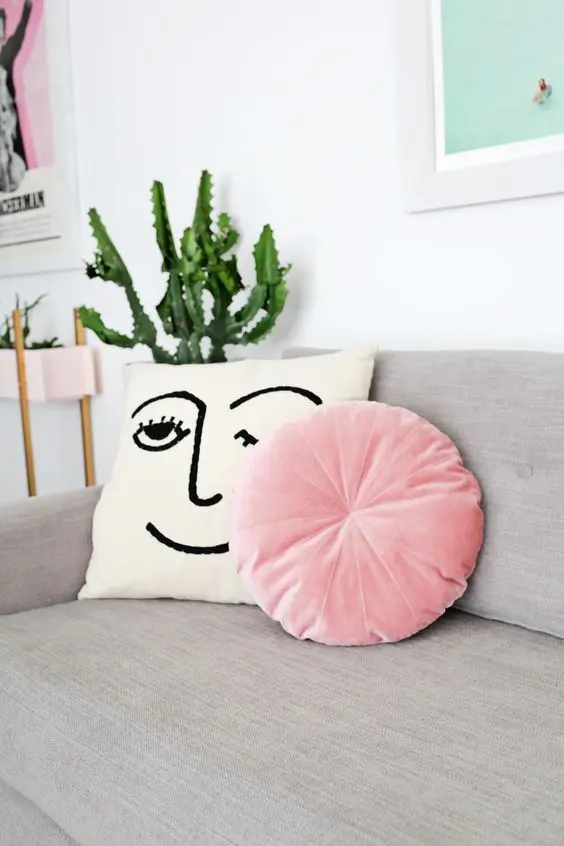 Almofada redonda rosa no sofá cinza
