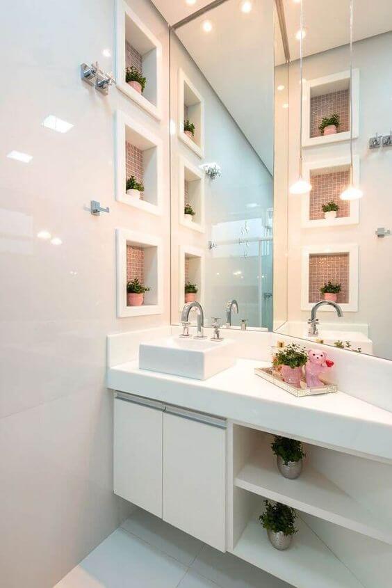 Nicho para banheiro de porcelanato branco decorado com pastilhas cor de rosa e vasos de plantas