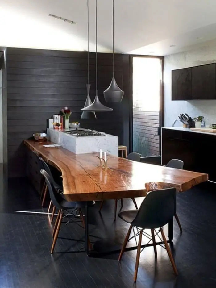 O piso fosco preto decora a cozinha planejada com mesa integrada à ilha. Fonte: Archlovers