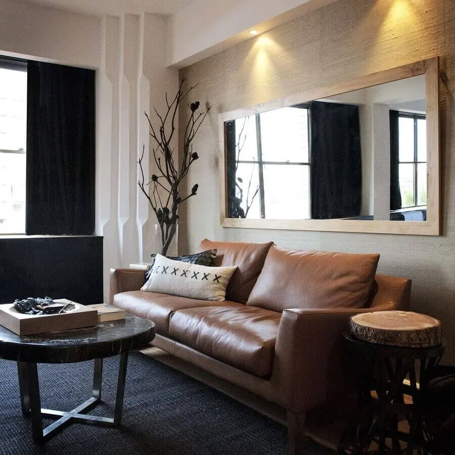 sala de visita decorada com sofá de couro e espelho com moldura de madeira Foto Pinterest