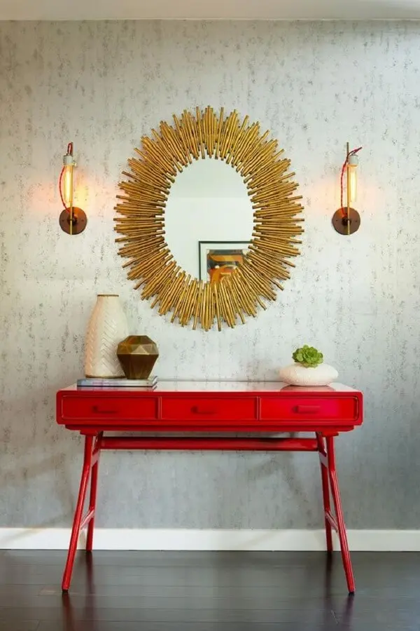 Aparador para sala pé palito vermelho e espelho dourado decoram o espaço. Fonte: Pinterest