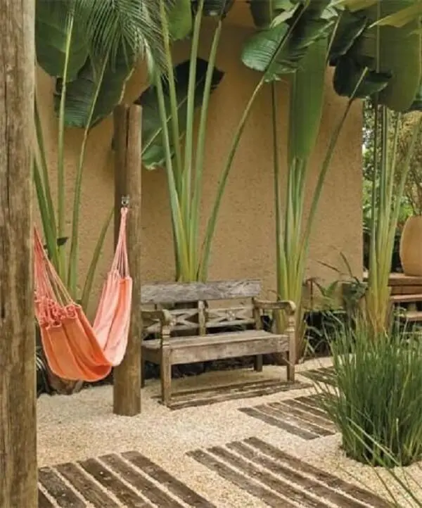 Espaço aconchegante com rede de descanso, banco d emadeira e jardim com pedras rústicas. Fonte: Pinterest