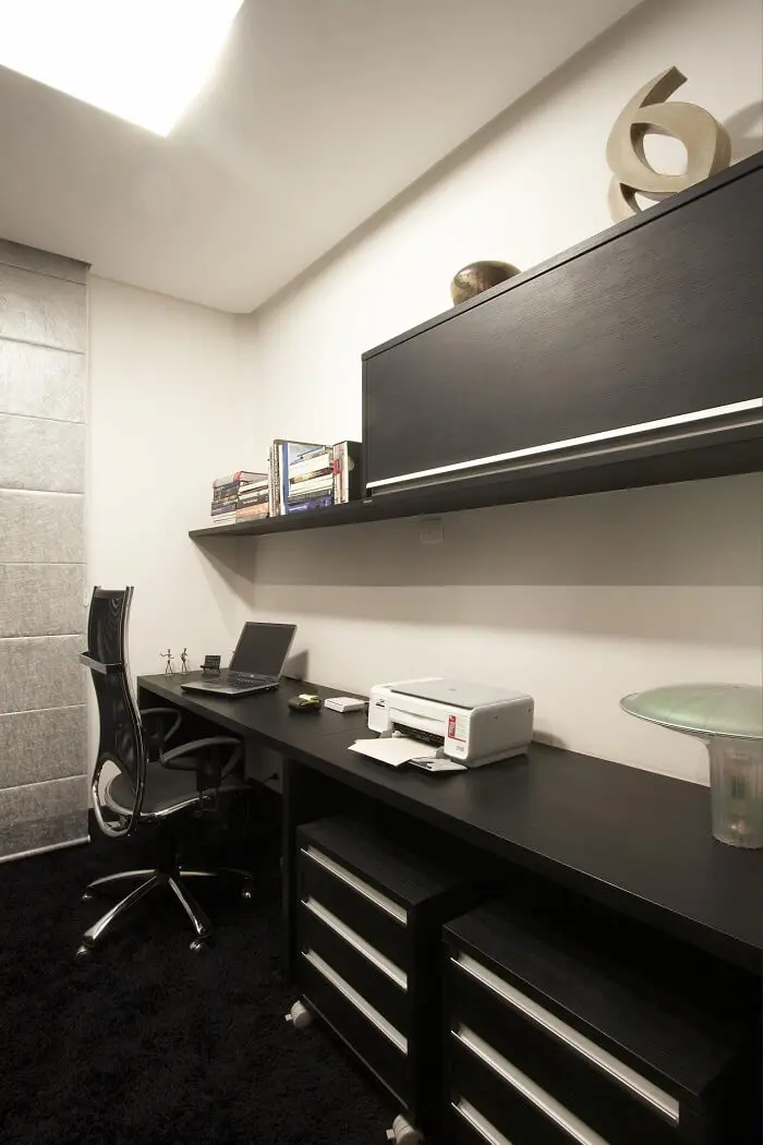 Home office sofisticado com bancada ampla e gaveteiro preto. Projeto de Léo Shehtman