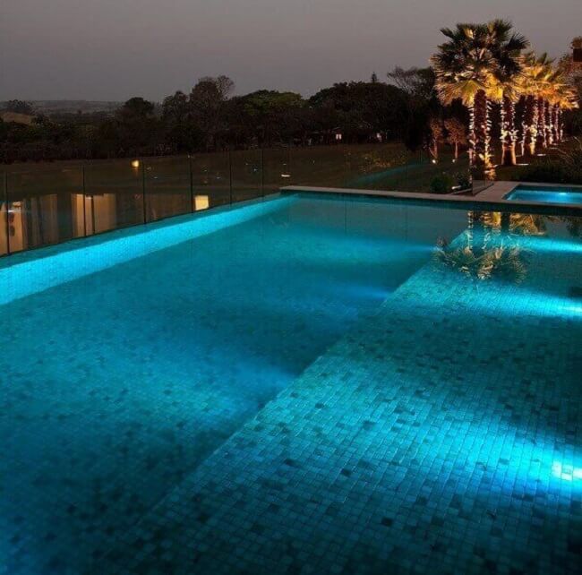 Linda piscina quadrada grande com borda infinita. Projeto de Zize Zink Arquitetura
