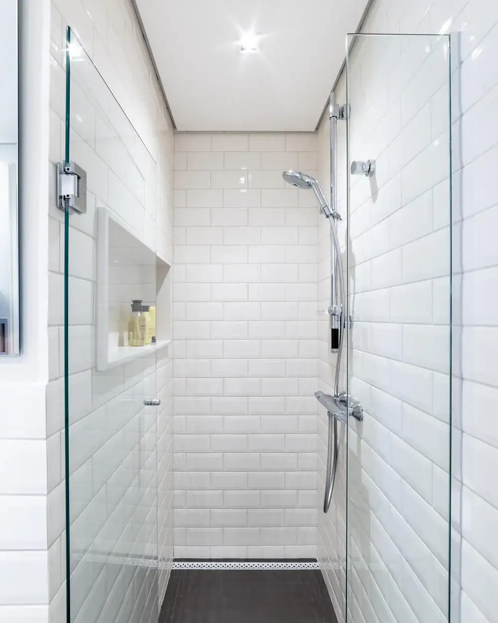 O banheiro do casal conta com piso de porcelanato escuro e azulejo metro white em toda a área do box. Foto: Guilherme Pucci