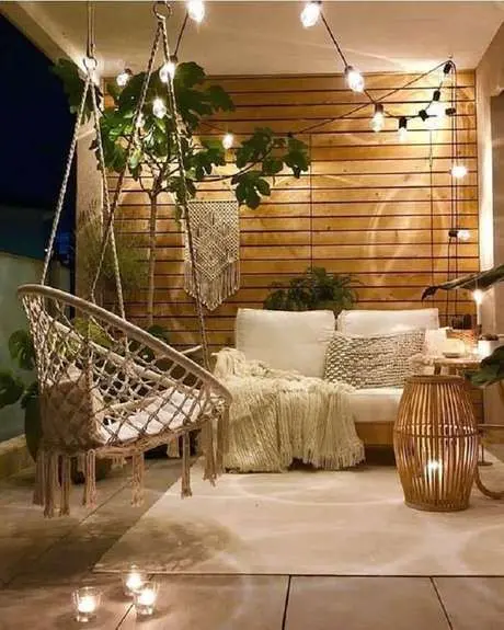 Sacada de madeira com iluminação romantica e móveis confortáveis