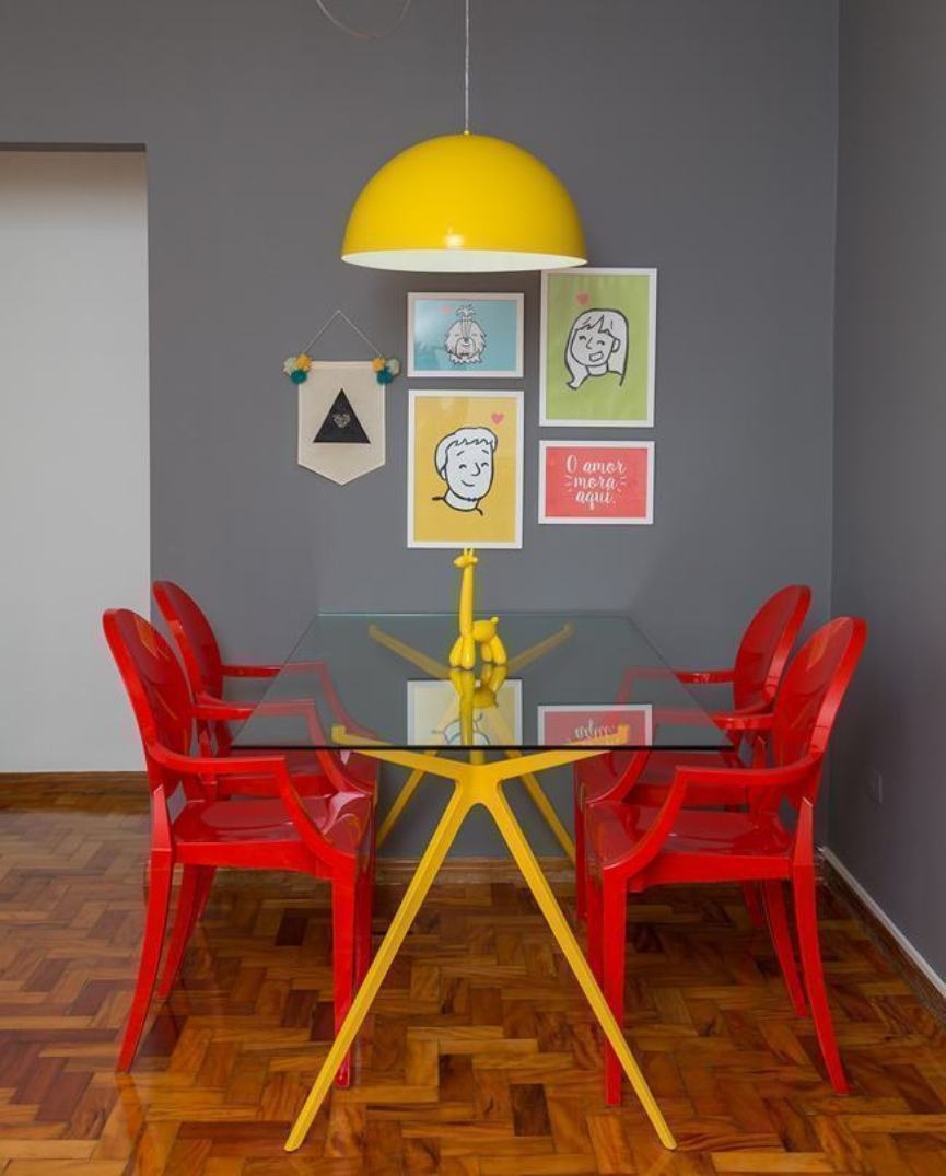 Sala de jantar com cadeira vermelha e lustre amarelo
