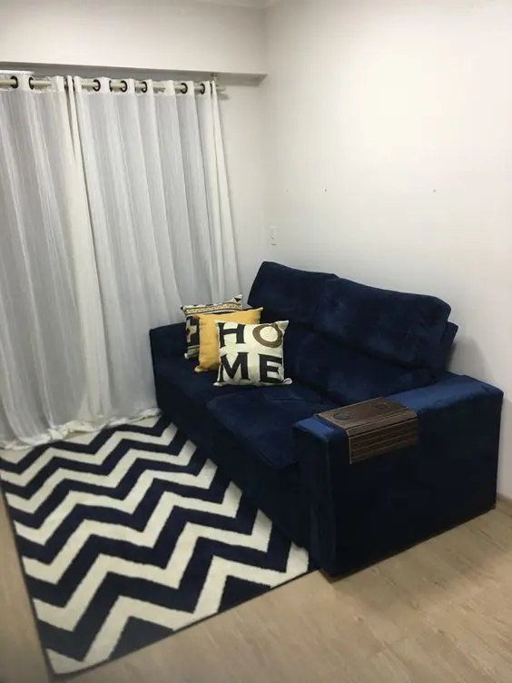 Sala pequena com sofá azul marinho e tapete chevron