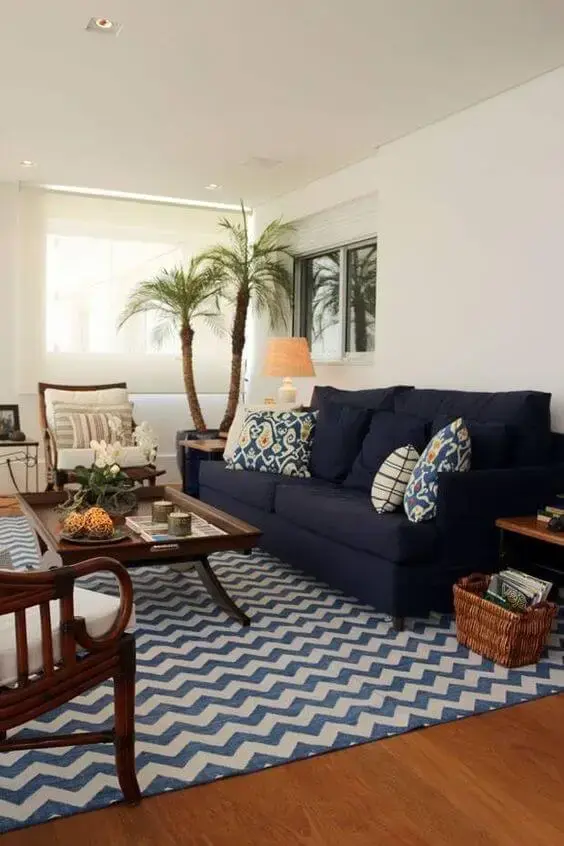 Tapete chevron em tons de azul e sofá azul marinho com móveis de madeira na sala