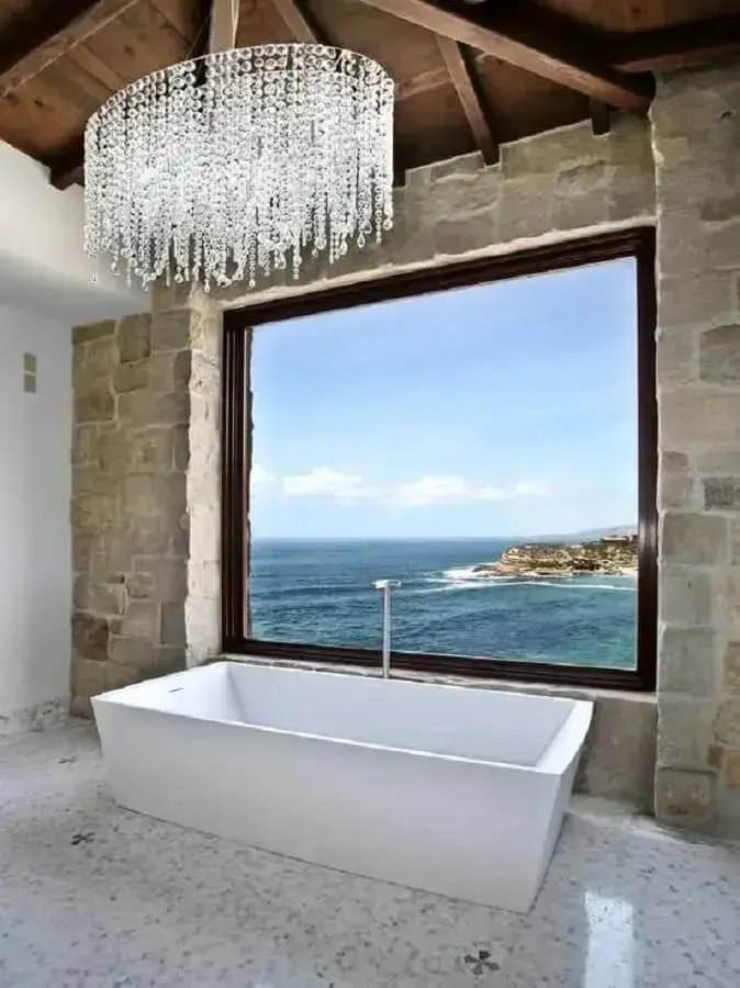 banheira de imersão para decoração de banheiro com lustre de cristal e parede rústica Foto Homedit