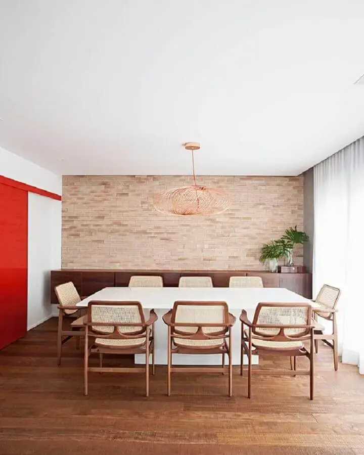 cadeira de jantar com braço para decoração de sala grande com parede tijolinho e mesa branca Foto Korman Arquitetos