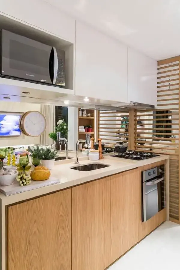 cozinha decorada com gabinete de madeira e armário suspenso branco com nicho para microondas Foto Jeito de Casa