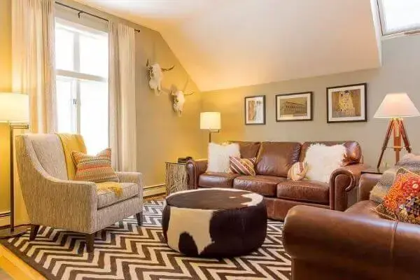 Sala de estar com tapete chevron marrom e sofá de couro
