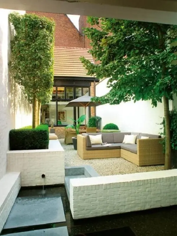 Área externa com móveis de vime e jardim com pedra branca. Fonte: Pinterest